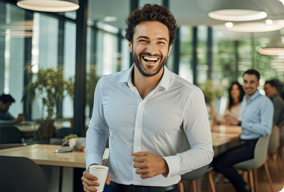 Person in office wearing a white shirt, holding a cup of coffee, smiling wide and cheerful